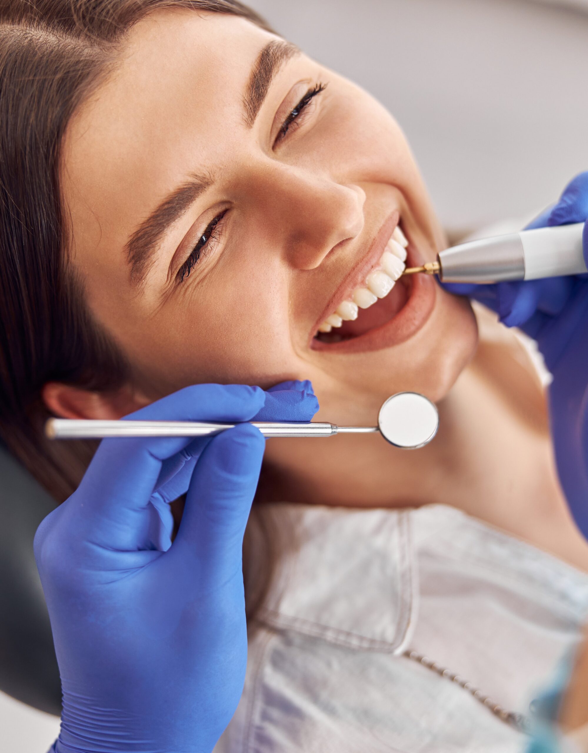 Female patient at dental procedure, doctor using dental instruments in modern dental clinic