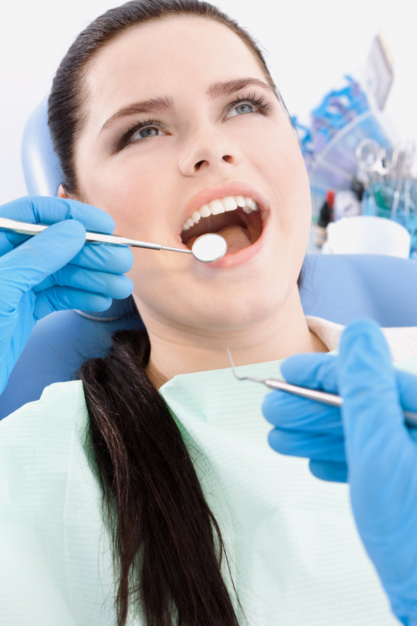 Dentist examines the mouth of the patient on the dentist's chair with the halp of dental mirror